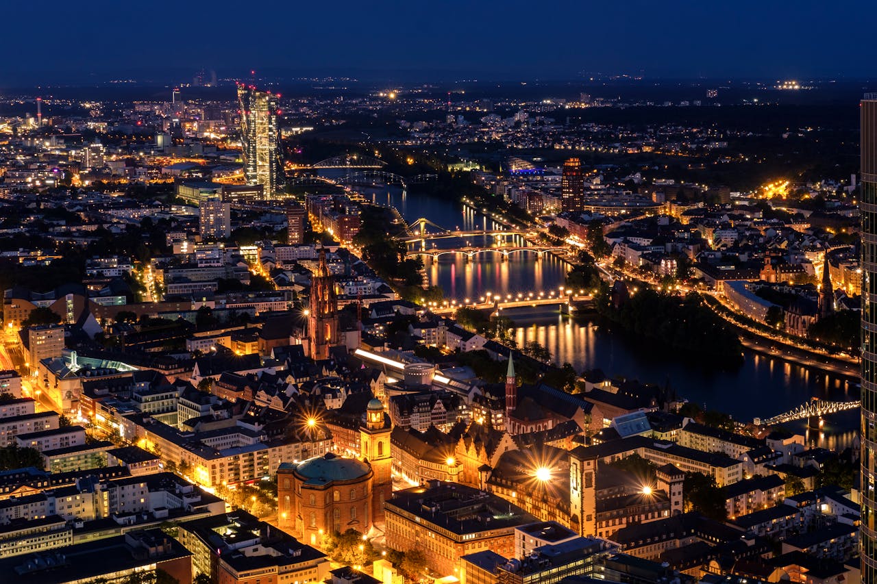 Stunning aerial view of Frankfurt illuminated at night showcasing modern skyline and river.